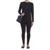 A person stands wearing a black long-sleeve top, black leggings, black shoes, and carrying the Clutch-Style Concealed Carry Purse with Shoulder Strap in Blue.
